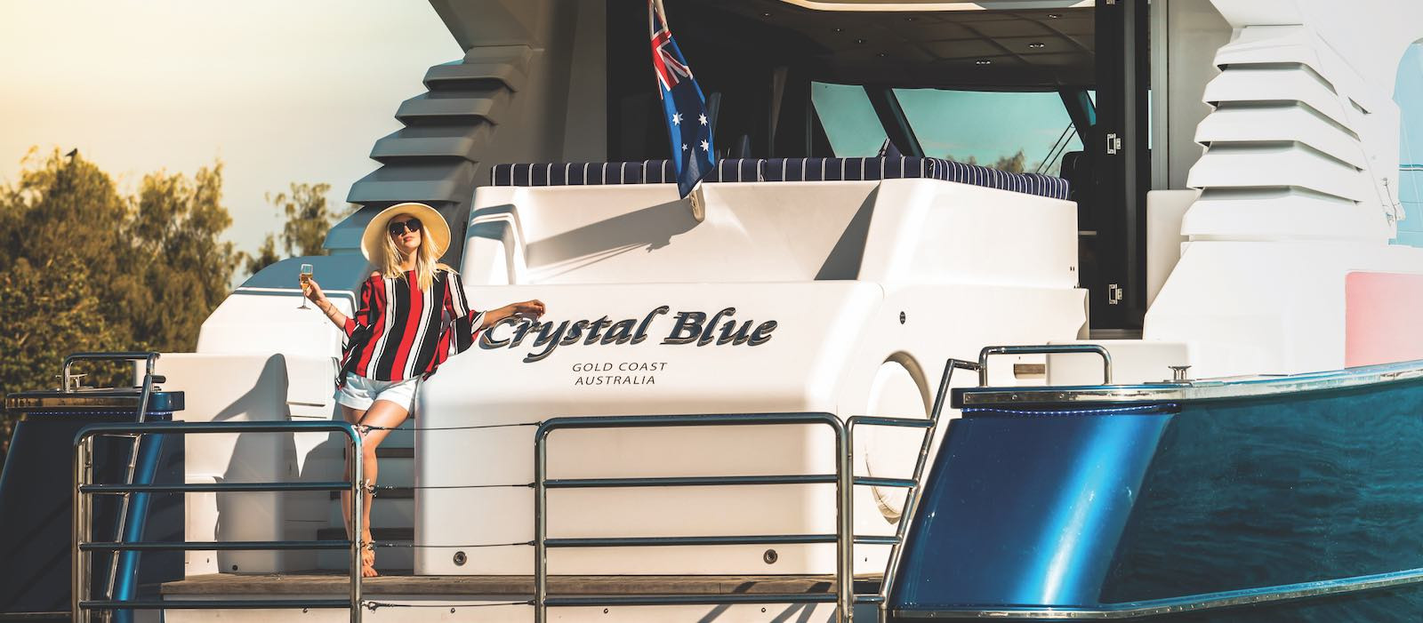 Luxury boat hire on Crystal Blue woman sipping champagne on swim deck
